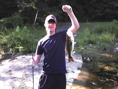 1996 Ford Bronco - A person proudly displays a freshly caught fish near a body of water.