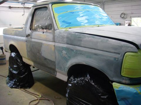 1996 Ford Bronco - A Ford Bronco is undergoing body repair, with its windows and lights taped off.