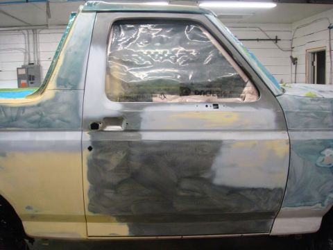 1996 Ford Bronco - A 1992 Ford Bronco is undergoing body repair, with its windows covered in plastic and the body prepped for paint.