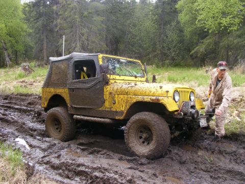 1981 Jeep CJ7 - Muddy yellow 1981 Jeep CJ7 navigating a difficult off-road trail.