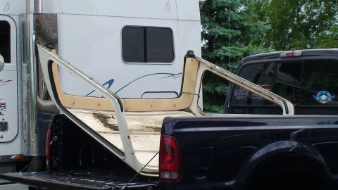 1979 Ford Bronco - A vehicle's removable hardtop is loaded into the bed of a dark-colored pickup truck.
