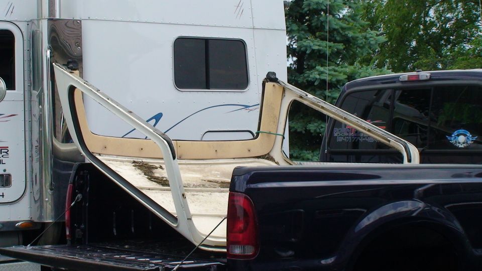 removable hardtop being transported in the bed of a pickup truck next to a semi-truck cab