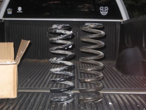 1995 Ford Bronco - Two coil springs are shown in the bed of a pickup truck, with a cardboard box to the left.