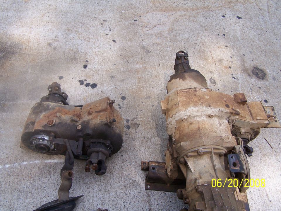 Two rusty transfer cases or gearboxes sitting on a concrete driveway