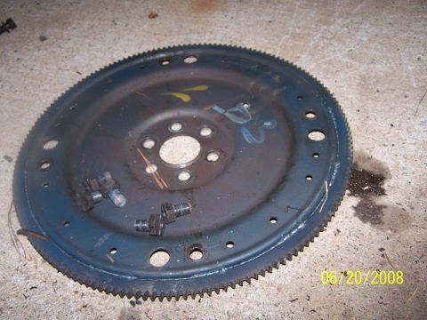 1979 Ford F-150 - A close-up view of a vehicle flywheel with bolts and markings, resting on a concrete surface.