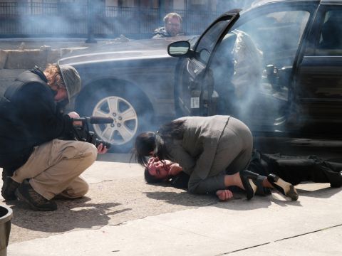 1985 Ford LTD Crown Victoria - Filming a dramatic scene involving a car and people on the ground, with smoke present.