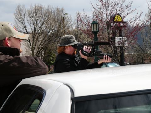 1985 Ford LTD Crown Victoria - A film crew captures footage from the interior of a vehicle, with a Days Inn sign visible in the background.