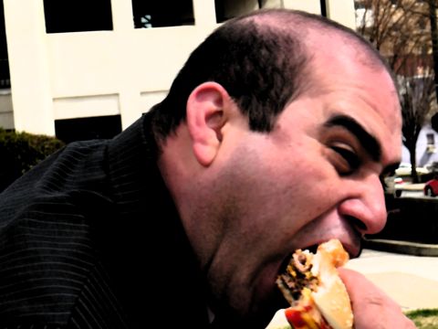 1985 Ford LTD Crown Victoria - A man takes a bite out of a large hamburger in this close-up profile shot.