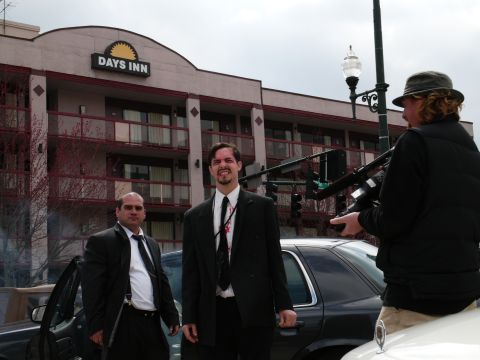 1985 Ford LTD Crown Victoria - A film crew captures a scene with actors in suits outside a Days Inn hotel.