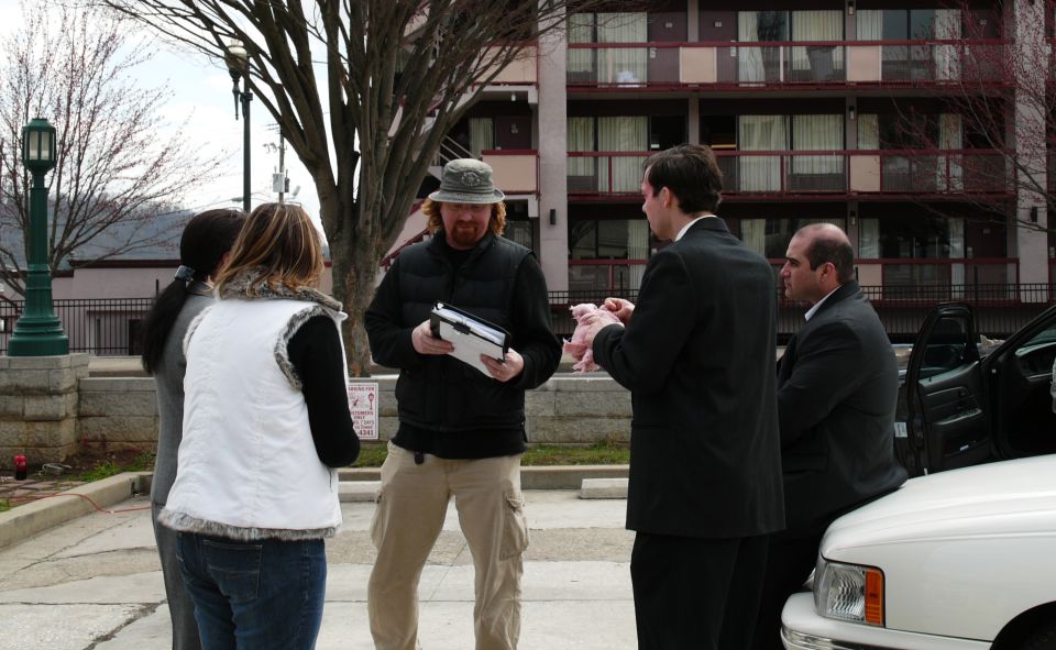 Group of people talking outside a motel, with a white car door open