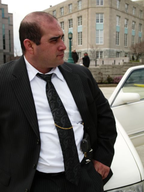 1985 Ford LTD Crown Victoria - A man in a suit leans against a white sedan.