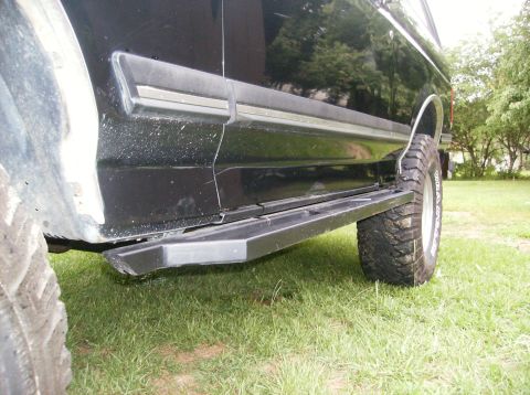 1990 Ford Bronco - The side view of a black Ford Bronco shows a black nerf bar or step installed below the doors. The vehicle is parked on a grassy area with…