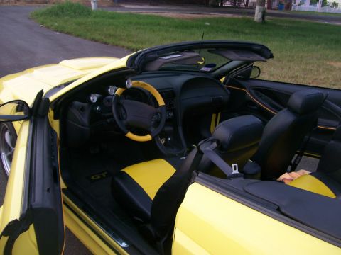 2001 Ford Mustang - The interior of a yellow convertible Mustang GT is shown with the driver's door open. The seats are black and yellow, and the steering whee…