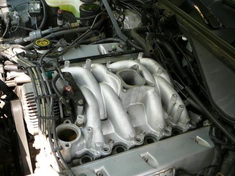 1997 Mercury Grand Marquis - Polished aluminum upper intake manifold of a V8 engine with visible fuel injector rails and wiring harness in an engine bay.