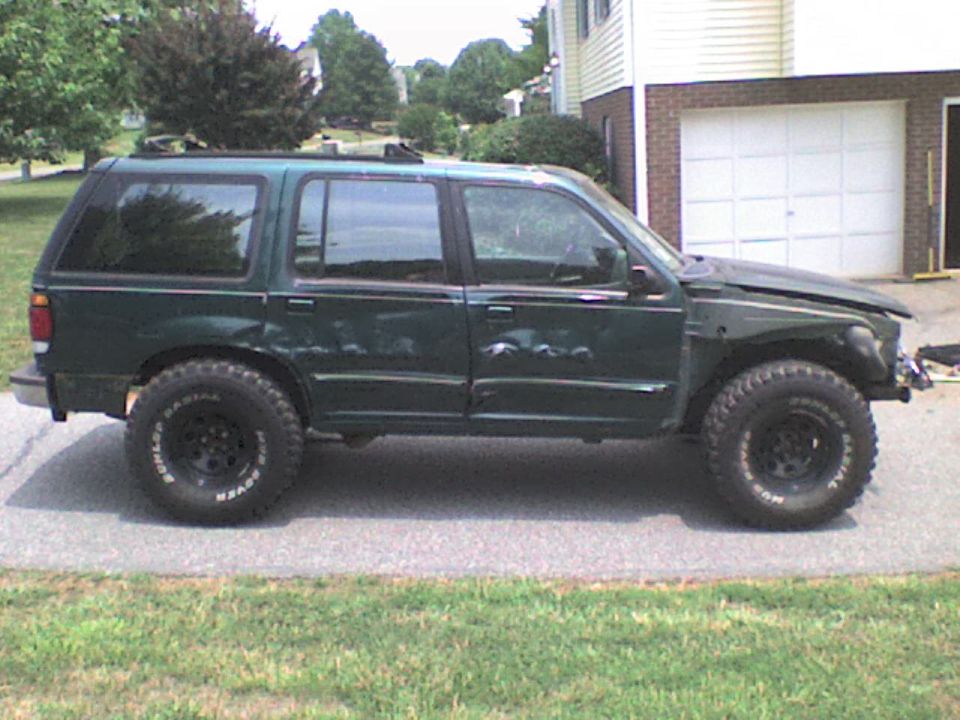 1995 Ford Explorer SUV with off-road tires parked on pavement.