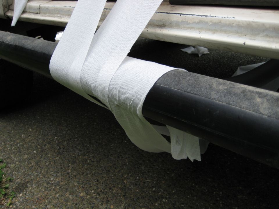 Black pipe wrapped in white tape attached to vehicle underside