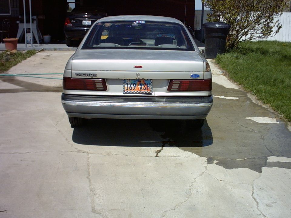 Rear view of a silver Ford Taurus sedan with Utah plate 169 XSH on a concrete driveway
