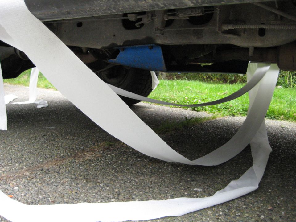 Toilet paper draped over the undercarriage of a vehicle.