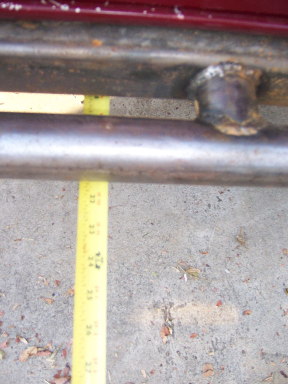 Welded steel tube bumper or frame with a tape measure laid across it on concrete