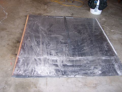 1991 Ford Bronco - Photograph of a large scuffed sheet of metal lying flat on a concrete garage floor.