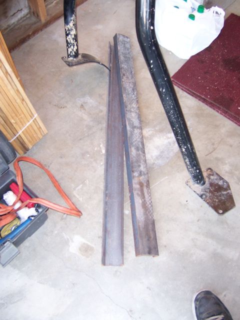 1991 Ford Bronco - Photograph of two lengths of steel channel stock lying on a garage floor beside a roll-cage tube.