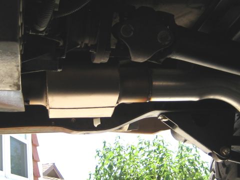 1996 Ford Bronco - The underside of a vehicle shows the exhaust system, including a muffler and pipes, with a driveshaft visible above. A portion of the vehic…