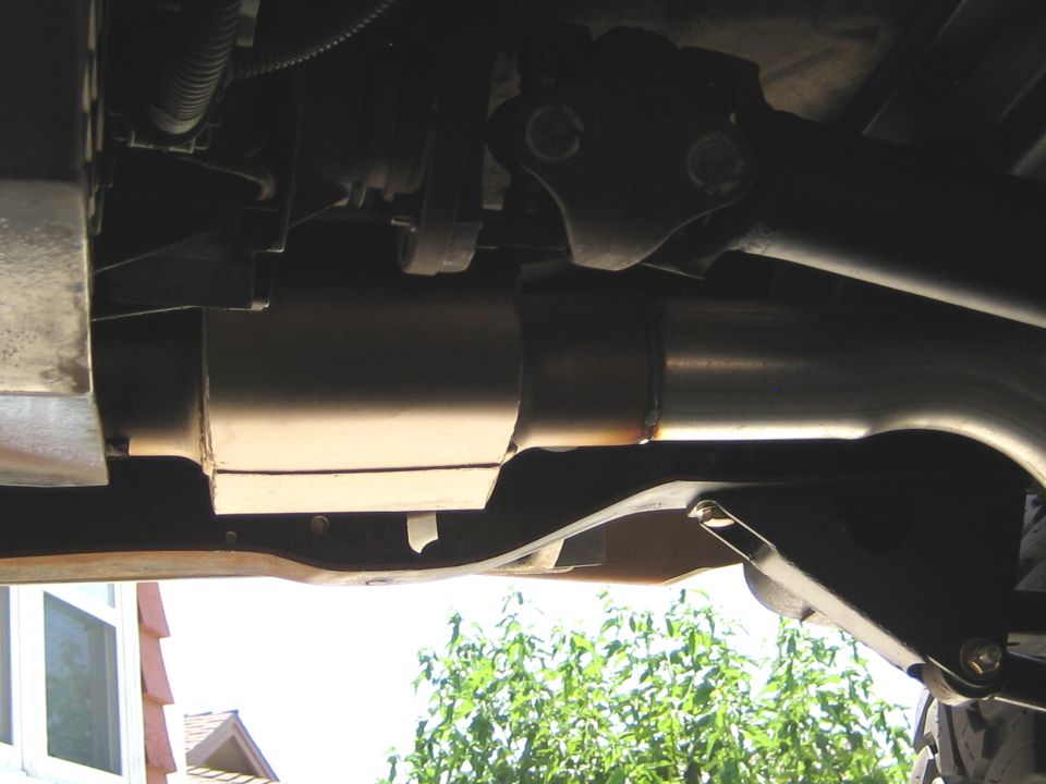 Underside of a vehicle showing exhaust system, driveshaft, and frame.