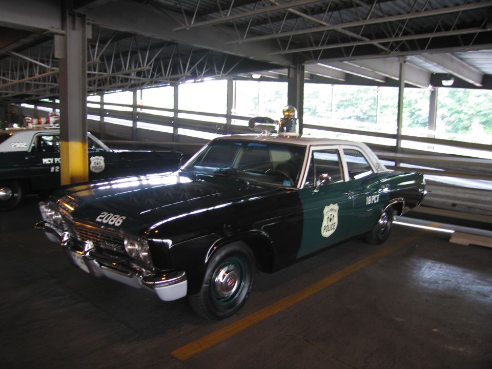 Vintage green-and-white NYC Police sedan marked 18 PCT and 2066 indoors