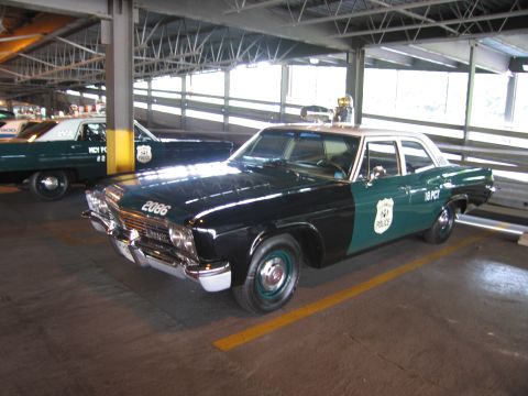 1991 Ford LTD Crown Victoria - vintage green-and-white police sedan numbered 2066 and marked 18 PCT parked among other patrol cars in a garage.