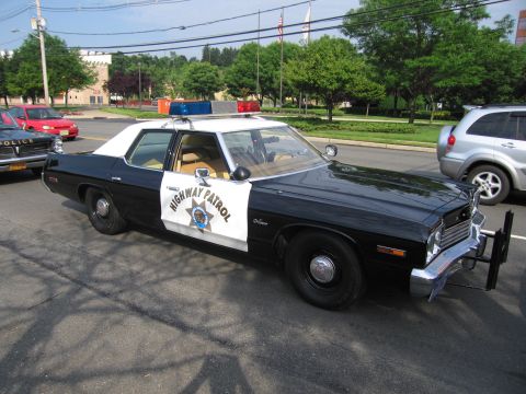 1991 Ford LTD Crown Victoria - black-and-white mid-1970s four-door California Highway Patrol sedan with door star shield, roof beacon and front push bar, parked in a lot.