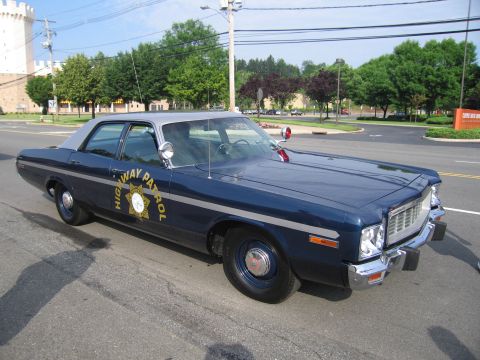 1991 Ford LTD Crown Victoria - dark blue mid-1970s four-door HIGHWAY PATROL sedan with gold door star, white roof and front push bar, parked on a street.