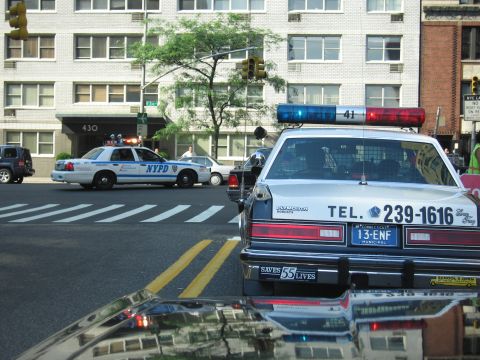 1991 Ford LTD Crown Victoria - NYPD Ford Crown Victoria sits at a Manhattan intersection, viewed past the trunk of a black-and-white police-style sedan marked TEL. 239-16…