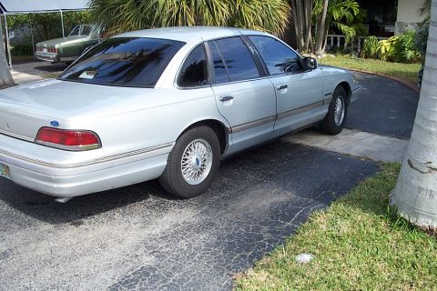 1992 Ford Crown Victoria - A silver sedan is parked in a driveway with a second vehicle visible in the background.