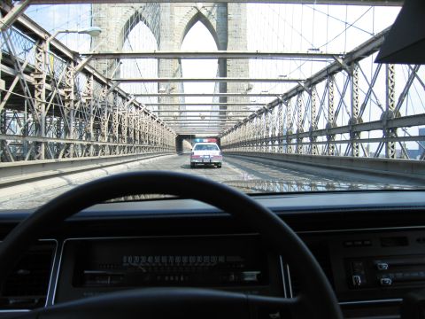 1991 Ford LTD Crown Victoria - From inside a car, a police-style sedan drives ahead between the cables and stone towers of the Brooklyn Bridge.