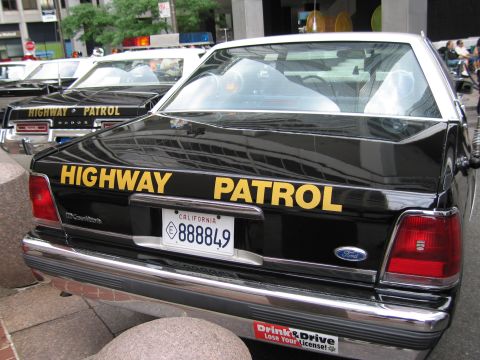 1991 Ford LTD Crown Victoria - black-and-yellow HIGHWAY PATROL Ford Crown Victoria with California plate 888849 displayed among other cruisers at a car show.