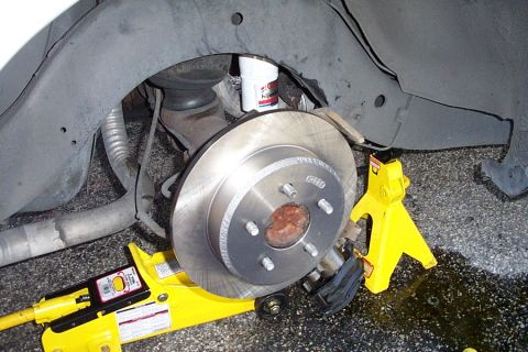 1992 Ford Crown Victoria - Close-up of a car's brake rotor and suspension system with tools for repair.