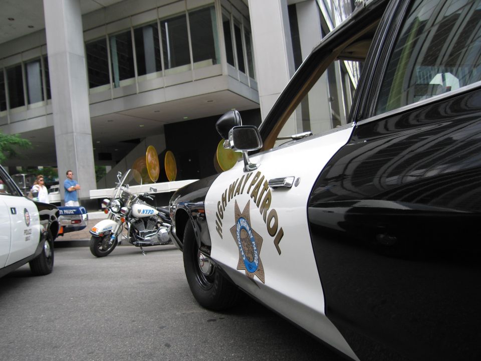 Side of black-and-white California Highway Patrol cruiser with motorcycle behind