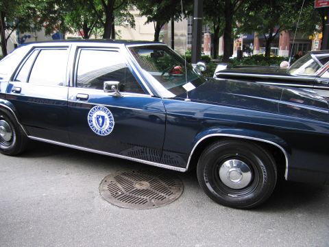 1991 Ford LTD Crown Victoria - Side profile of a dark blue Massachusetts State Police Ford LTD Crown Victoria sedan showing the state seal door emblem.