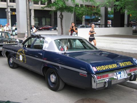 1991 Ford LTD Crown Victoria - Rear three-quarter view of a dark blue Dodge HIGHWAY PATROL sedan with dual spotlights and star emblem parked on a city street.