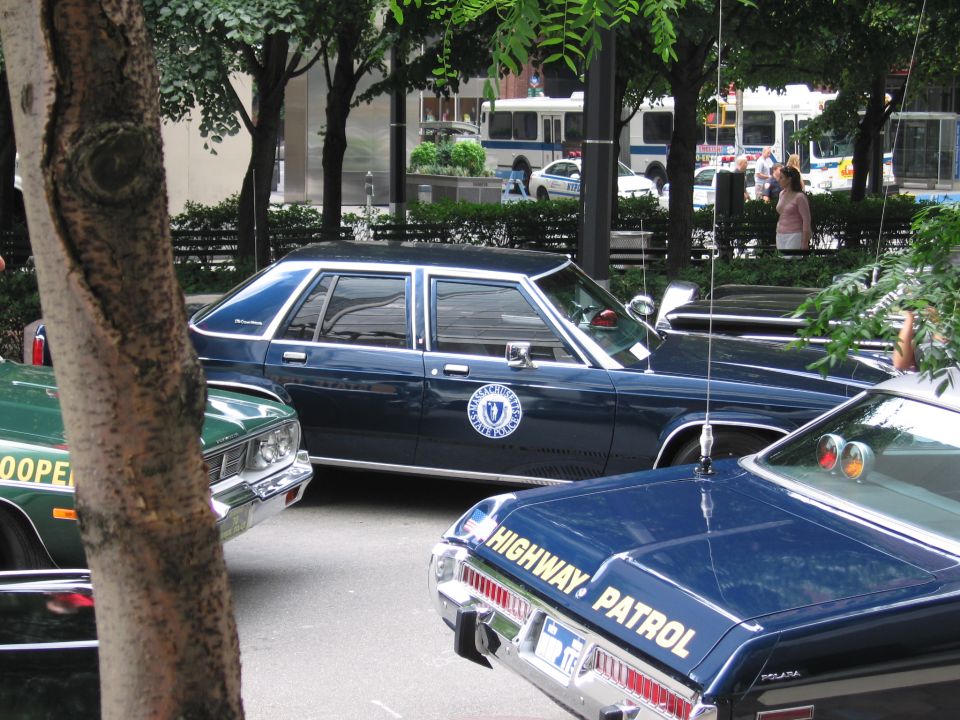 Dark blue state police sedan with seal, green trooper car and black highway patrol car
