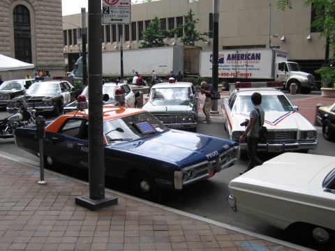 1991 Ford LTD Crown Victoria - row of vintage police cars including a dark blue Nassau County cruiser sits on a brick plaza at a downtown car show.