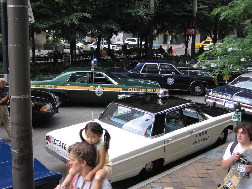 Vintage state police and trooper cars including a green and a white sedan at a show