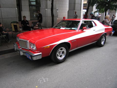 1991 Ford LTD Crown Victoria - red Ford Gran Torino coupe with a white side stripe, like the Starsky and Hutch car, is parked on a city street near spectators.