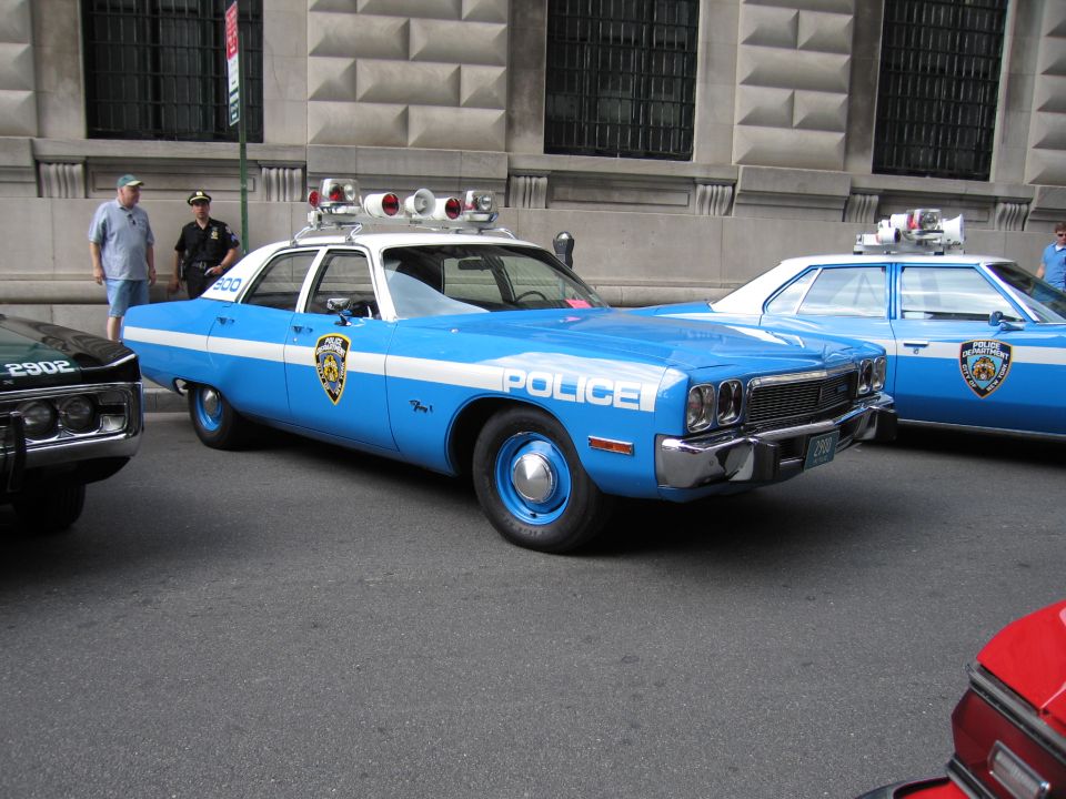 Light blue and white vintage NYPD police sedan with roof lights at the curb