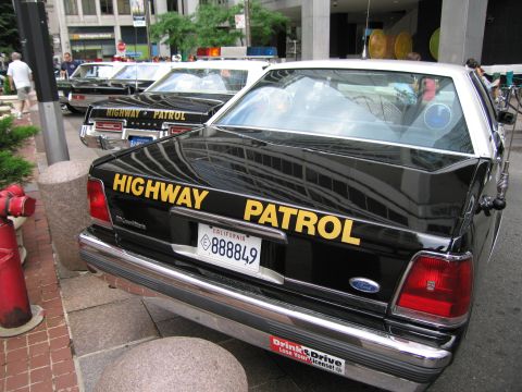 1991 Ford LTD Crown Victoria - black rear of a Ford Crown Victoria California Highway Patrol cruiser with yellow lettering and a California plate at a car show.