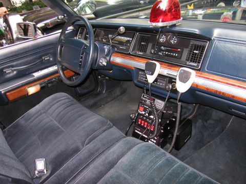 1991 Ford LTD Crown Victoria - blue interior of a vintage police car with twin handset radios, a control panel and a red dome light on the dashboard.