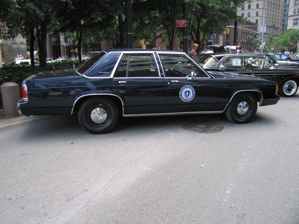 Dark blue Ford LTD Crown Victoria police sedan with state seal, parked on city street