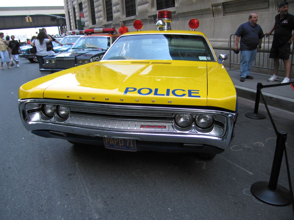 Front of yellow Plymouth POLICE sedan with PAPD 71 plate and roof beacons