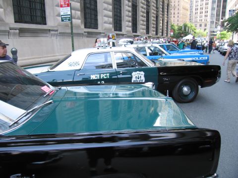 1991 Ford LTD Crown Victoria - vintage New York City Police green-and-white sedan marked MCY PCT sits among other classic squad cars on a downtown street.