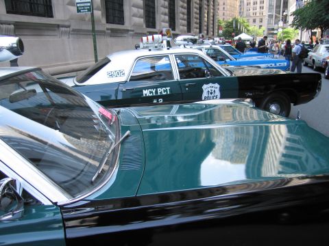 1991 Ford LTD Crown Victoria - Sunlight reflects off the roof and trunk of a vintage New York City Police sedan parked among other classic cruisers downtown.